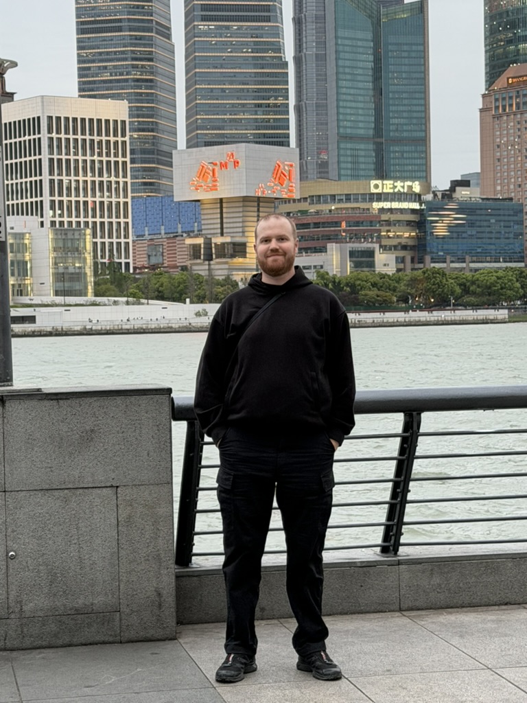 Matt standing beside a waterfront in a black hoodie, 8 April 2026.